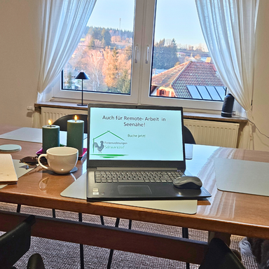 Großer Esstisch in der Ferienwohnung Hanfdell mit Laptop und Blick in die Natur, heller und gemütlicher Arbeits- und Essbereich.