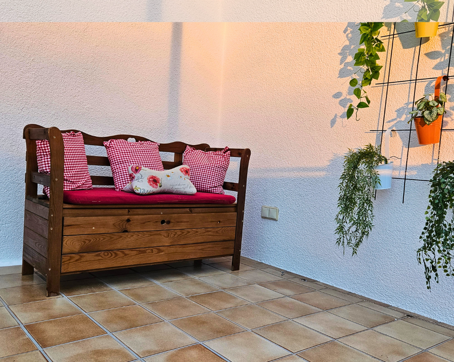 Sitzbank auf dem sonnigen Balkon der Ferienwohnung Hahnekräh mit bunten Blumentöpfen und Hängepflanzen