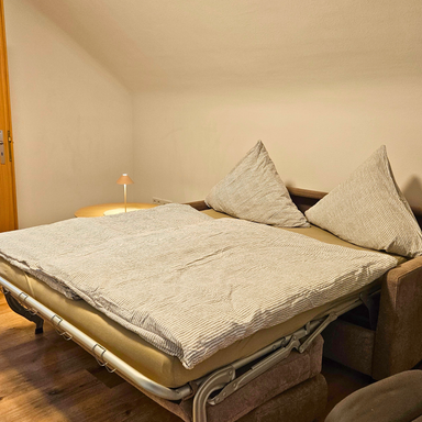 Ausgeklappte Dauerschlafcouch im Wohnzimmer der Ferienwohnung Hahnekräh, 1,40 m Bett für Gäste.
