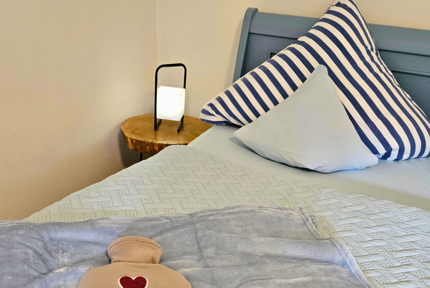 Detail eines Bettes mit Kissen und Kuscheldecke im warmen Abendlicht in den Ferienwohnungen Schwarzhof am Bostalsee