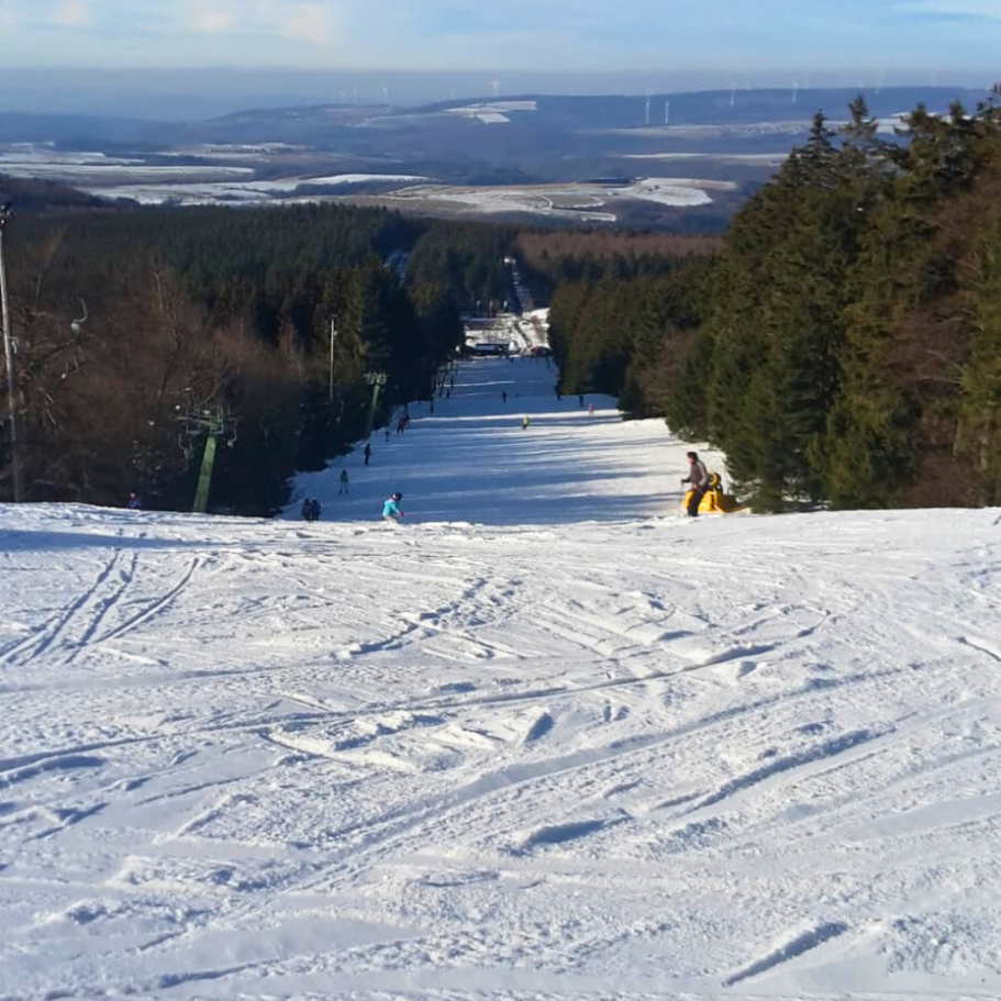 Wintersport am Erbeskopf: Skifahrer auf der Piste mit Panoramablick über die Winterlandschaft nahe den Ferienwohnungen Schwarzhof.