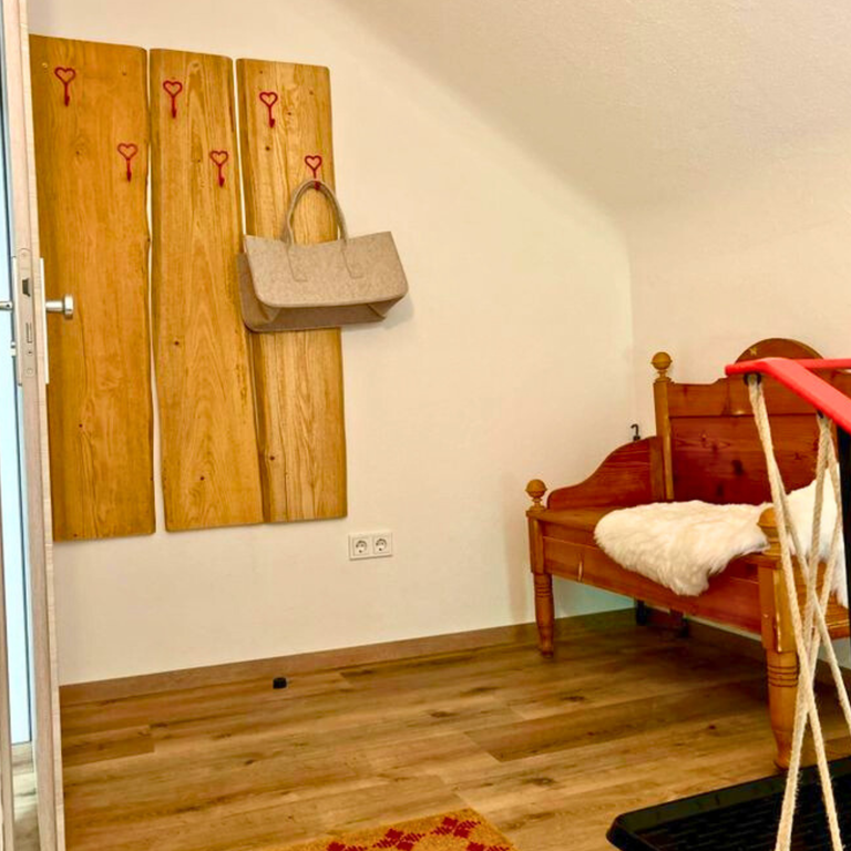 Ferienwohnung Hahnekräh Eingangsbereich mit antiker Truhenbank, Hausschuhen und Garderobe – Ankommen. Wohlfühlen. Lächeln.