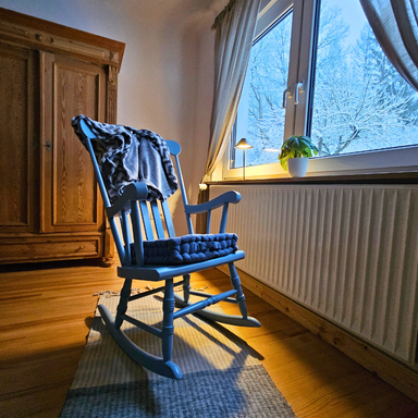 Ferienwohnungen Schwarzhof Bostalsee – Schaukelstuhl im Schlafzimmer der Fewo Hanfdell, Blick auf verschneite Landschaft