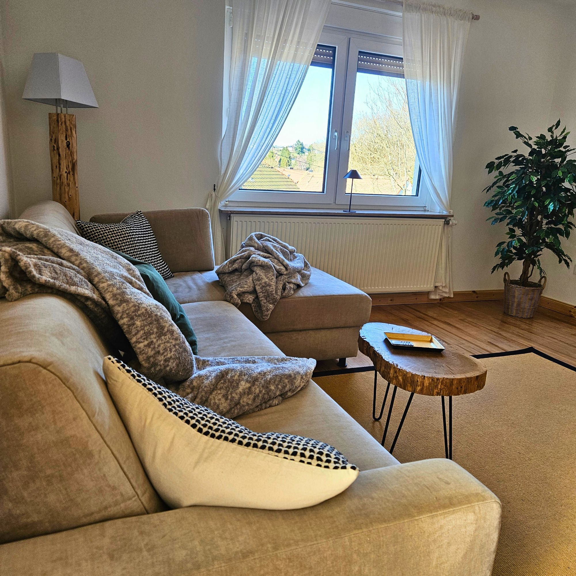 Helles Wohnzimmer der Ferienwohnung Schwarzhof Hanfdell nahe Bostalsee mit Sofa und Blick ins Grüne