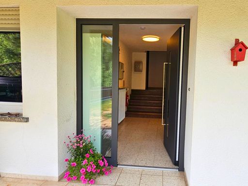 Eingang zum Ferienhaus am Gestüt Nahetal mit geöffneter Haustür und Blumenschmuck