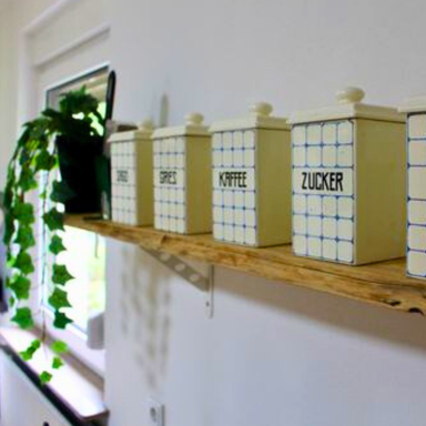 Wohnküche der Ferienwohnung Hahnekräh, Detail des Regals mit antiken Vorratsdosen und Efeu.